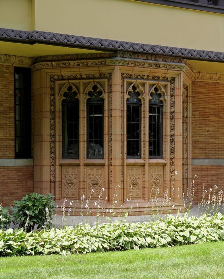 Nathan Moore House in Oak Park, Illinois, designed by Frank Lloyd Wright. The historic Tudor Revival-style residence features intricate architectural details and lush greenery surrounding the property.