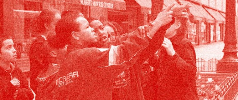 A group of children pointing at a building. The photo has a red overlay