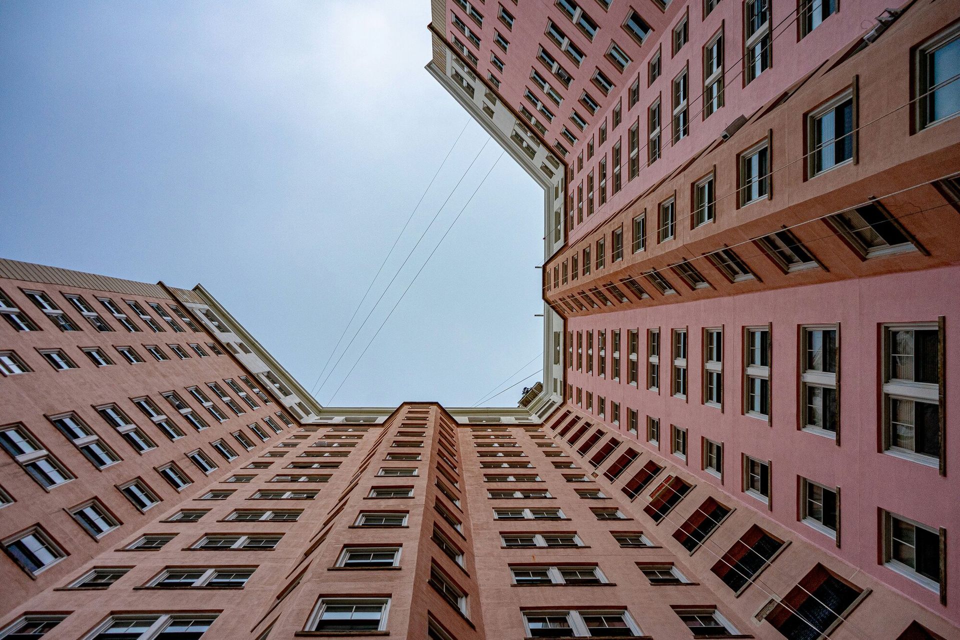 looking up at a tall pink building that is c shaped.