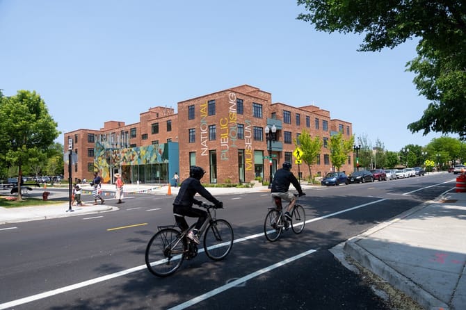 Two bicyclists riding toward a building in the city
