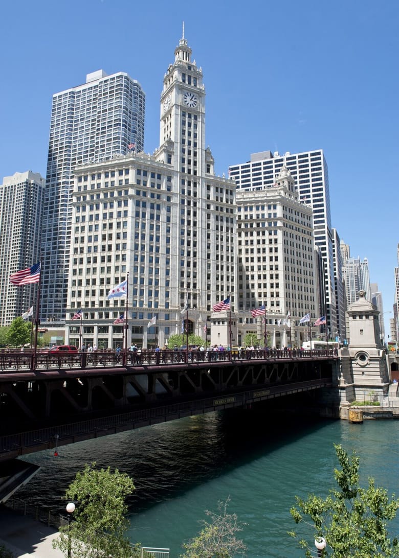 Looking across river and bridge at white multi-story building.