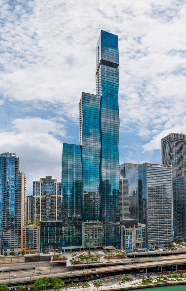 One building comprised of 3 glass towers, against cloudy sky.